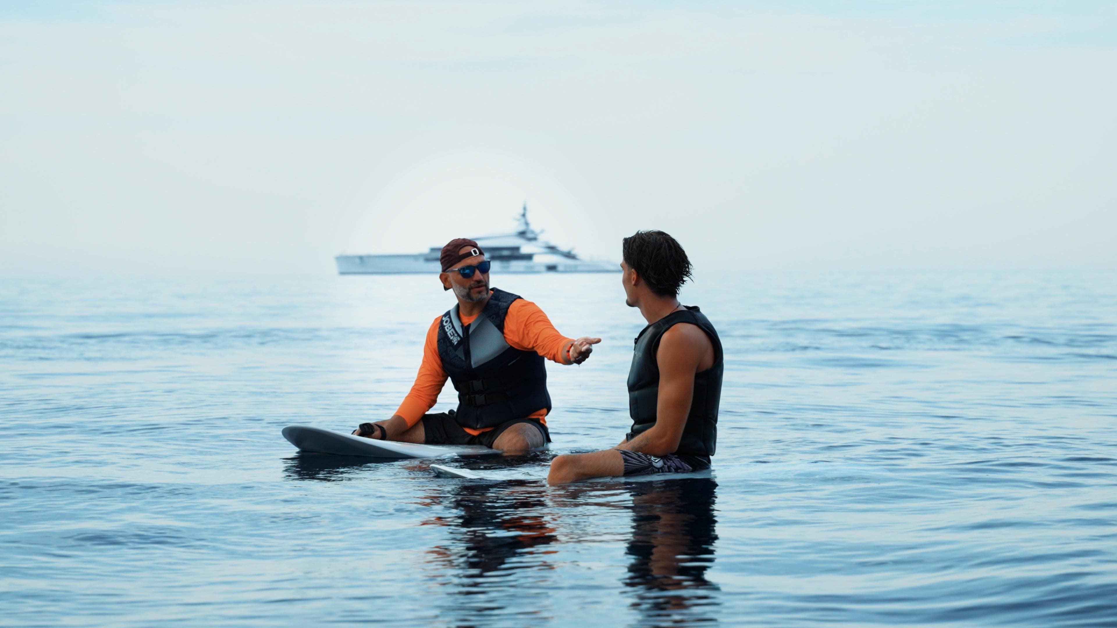 Instructor coaching a guest sitting on boards in glassy water